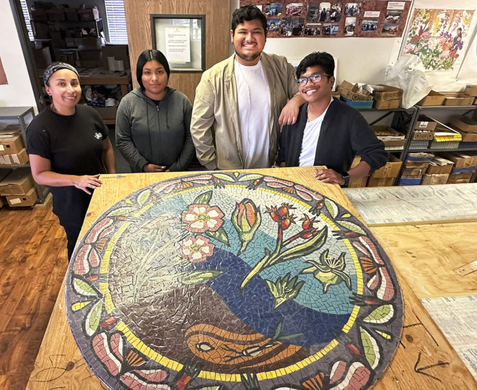 Mosaic-art-1 Four young people standing behind a round mosaic artwork