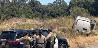 sheriffs look on at van that skidded off the road
