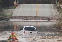 A State Parks Rescue swimmer paddles to shore from a pickup that stalled in flood water on Paulsen Road in 2023. New funding could help prevent this annual event.