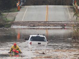 A State Parks Rescue swimmer paddles to shore from a pickup that stalled in flood water on Paulsen Road in 2023. New funding could help prevent this annual event.