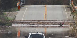 A State Parks Rescue swimmer paddles to shore from a pickup that stalled in flood water on Paulsen Road in 2023. New funding could help prevent this annual event.