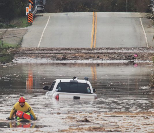 A State Parks Rescue swimmer paddles to shore from a pickup that stalled in flood water on Paulsen Road in 2023. New funding could help prevent this annual event.