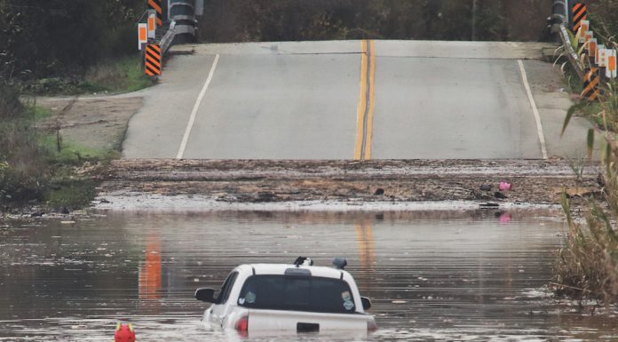 A State Parks Rescue swimmer paddles to shore from a pickup that stalled in flood water on Paulsen Road in 2023. New funding could help prevent this annual event.