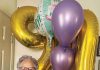 Betty Bobeda poses in front of the balloons she received for her 90th birthday