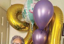 Betty Bobeda poses in front of the balloons she received for her 90th birthday