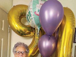 Betty Bobeda poses in front of the balloons she received for her 90th birthday