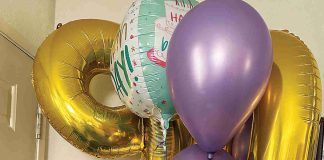 Betty Bobeda poses in front of the balloons she received for her 90th birthday