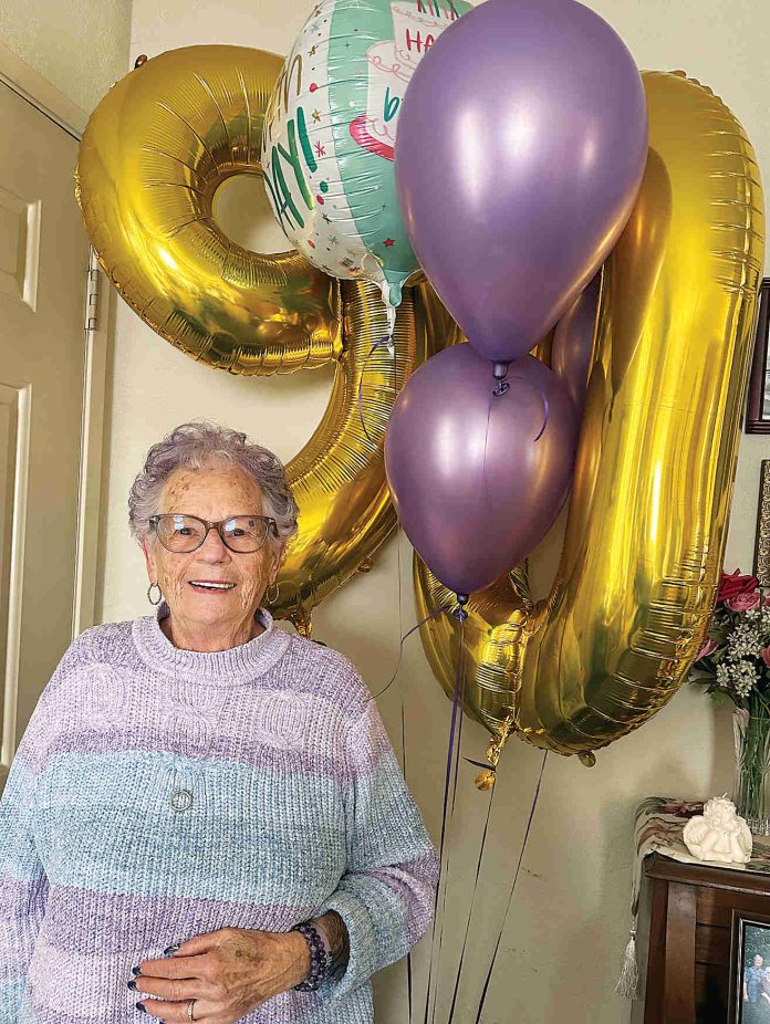 Betty Bobeda poses in front of the balloons she received for her 90th birthday