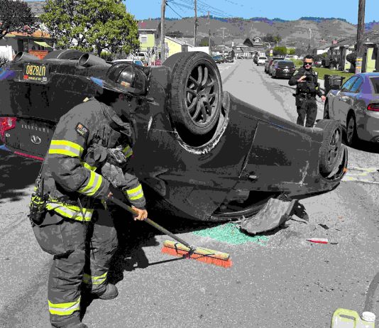 A Watsonville firefighter cleans up at the scene of a two-vehicle crash Tuesday afternoon on Center Street in Watsonville.