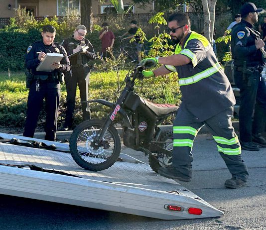A tow operator lifts one of two electric dirt bikes onto a flatbed truck after being stopped by Watsonville Police