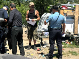 A “Notice To Vacate” flier is handed to Edward Lovell Thursday where he lives at a homeless encampment on Airport Boulevard.
