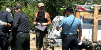 A “Notice To Vacate” flier is handed to Edward Lovell Thursday where he lives at a homeless encampment on Airport Boulevard.