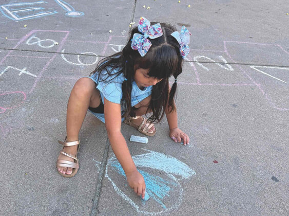 Paloma Espinosa, 4, enjoys creating a drawing with chalk at the Youth Center.