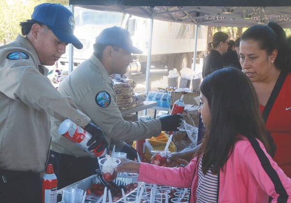 Members of the California Conservation Corps hand out strawberries with whipped cream at Pinto Lake County Park as part of the Santa Cruz County Sheriff&rsquo;s hosting of National Night Out.