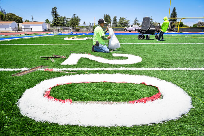 Juan replaces the turf on the 20-yard line on Tom Burt Field at Los Altos High School Stadium.